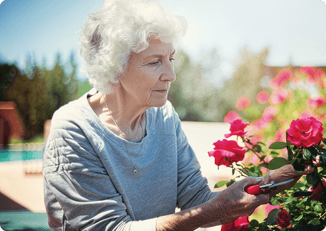 Older woman with white hair sitting outdoors near flowers, representing daily activities affected by GA progression